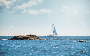 Sailboat cruising thru archipelago with watersplash in the foreground Sweden